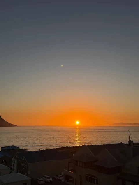 Sunset above a coastal town and calm water.